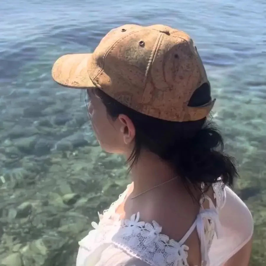 Woman wearing cork cap looking out at body of water.