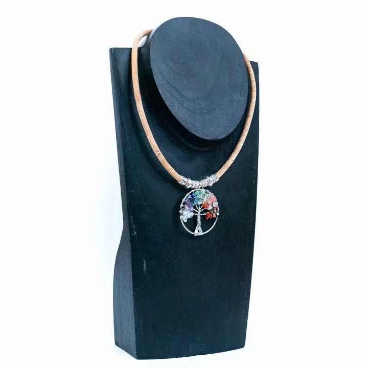 Necklace with a colorful tree pendant on a black stand against a white background