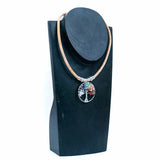 Necklace with a colorful tree pendant on a black stand against a white background