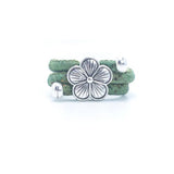 Green cork ring with a silver vintage floral charm on a white background