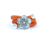 Orange cork ring with a silver vintage floral charm on a white background