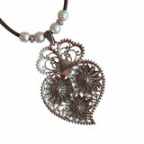 Decorative antique floral pendant and pearl beads closeup back on a white background