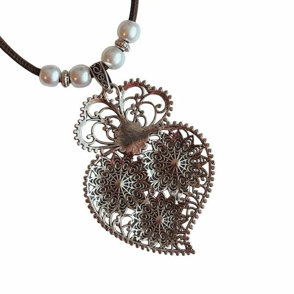 Decorative antique floral pendant and pearl beads closeup back on a white background