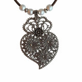 Close-up of antique floral pendant and brown cork cord