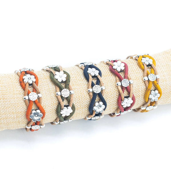 Five braided cork cord bracelets with silver-tone daisy floral charms and beads, displayed on a beige fabric ring holder against a white background.
