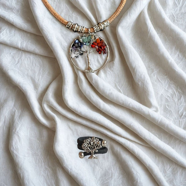 Necklace with a tree of life pendant and a cork ring with a tree pendant on a white fabric background