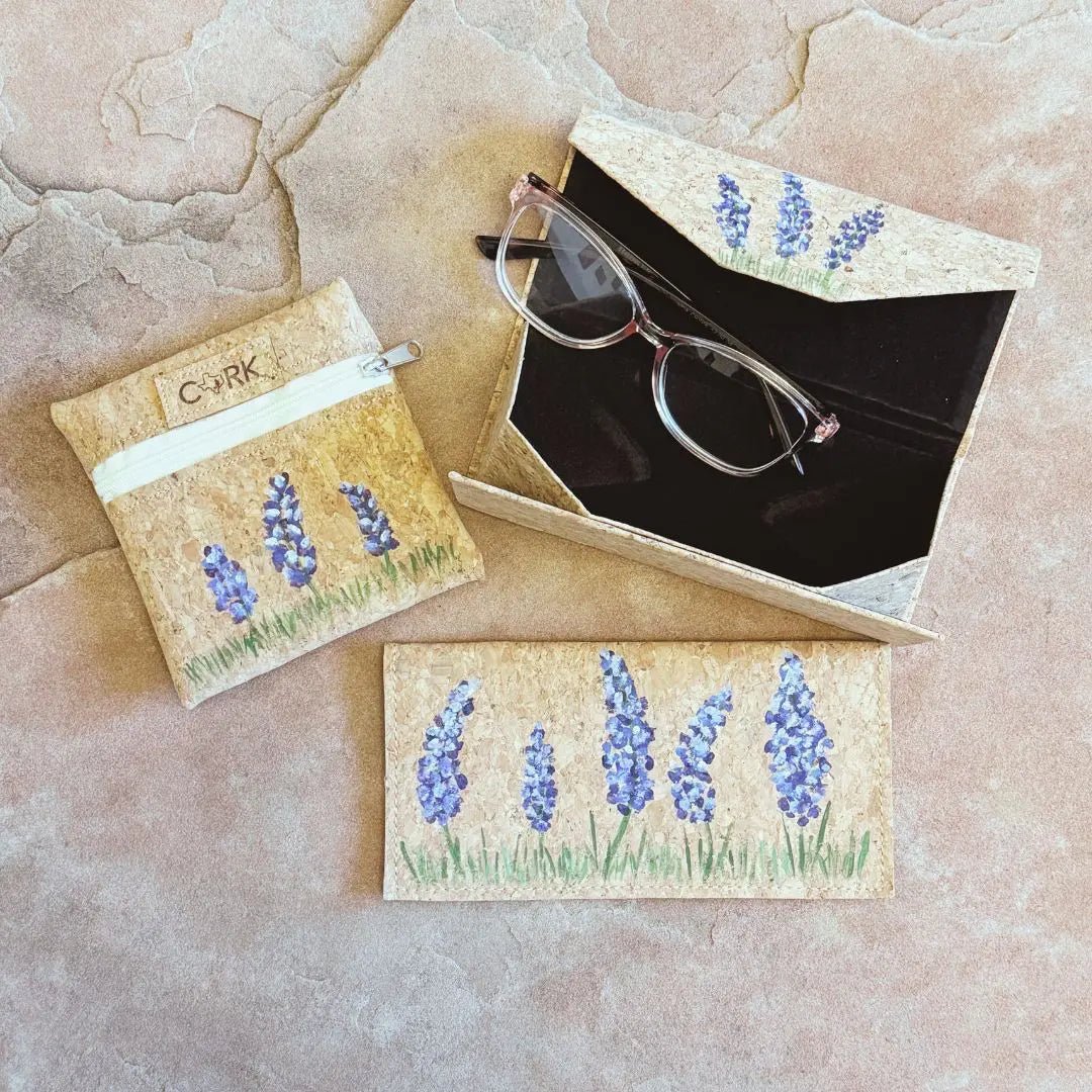 Cork coin pouch, checkbook cover, and open glasses case bundle on stone background