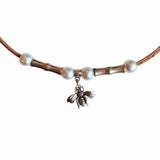 Close up of cork necklace with pearl beads and a bee charm on a white background