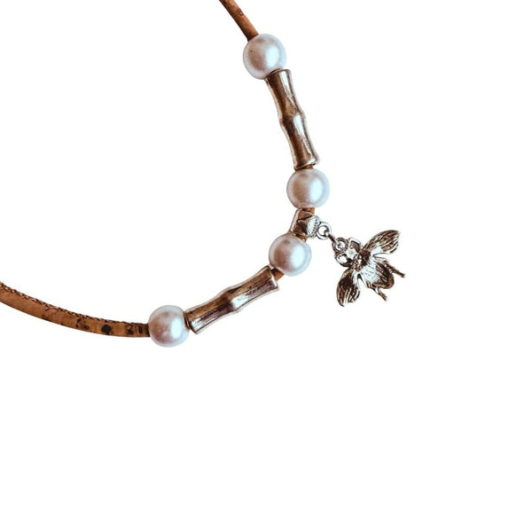 Necklace with pearl beads and back of the bee charm on a white background