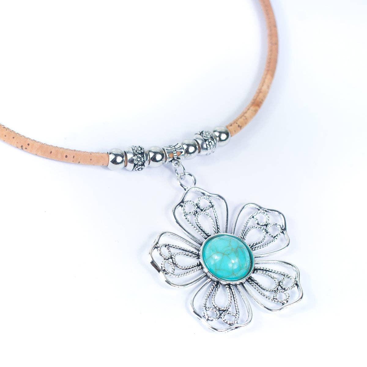 Closeup of pendant on cork cord with turquoise ceramic and zamak flower from Texas Cork Company