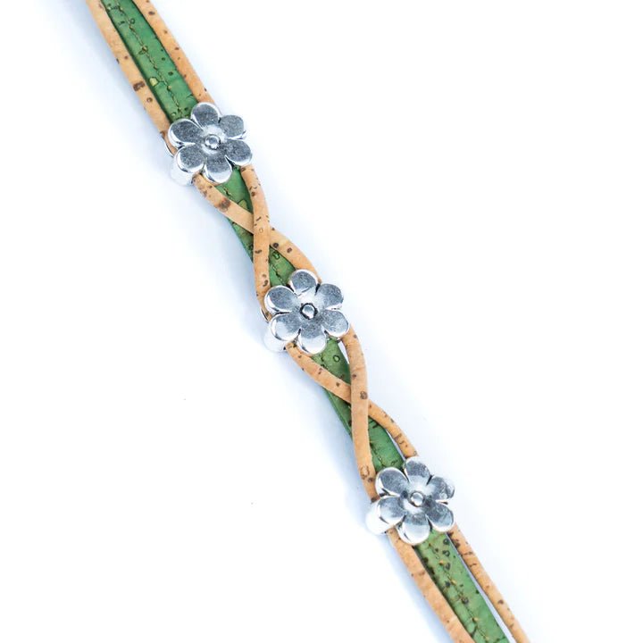 Bracelet with green and natural twisted design and silver daisy charms lying flat on a white background