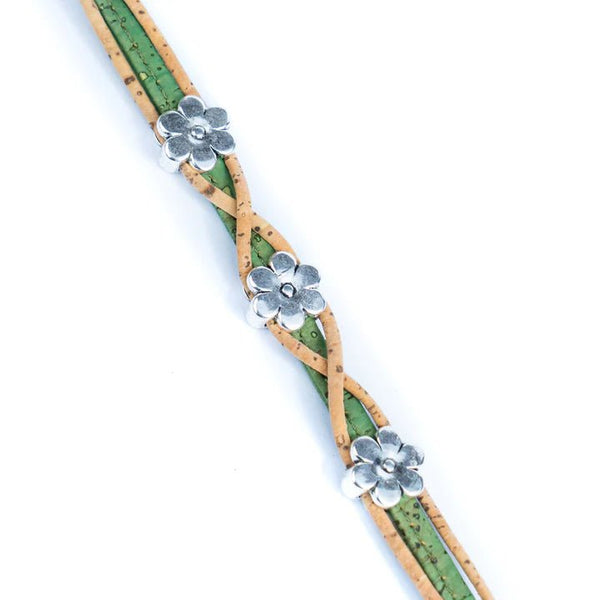 Bracelet with green and natural twisted design and silver daisy charms lying flat on a white background