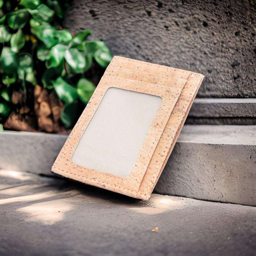 Minimalist cork card wallet with RFID protection and ID window on cement step outside with plants in background from Texas Cork Company