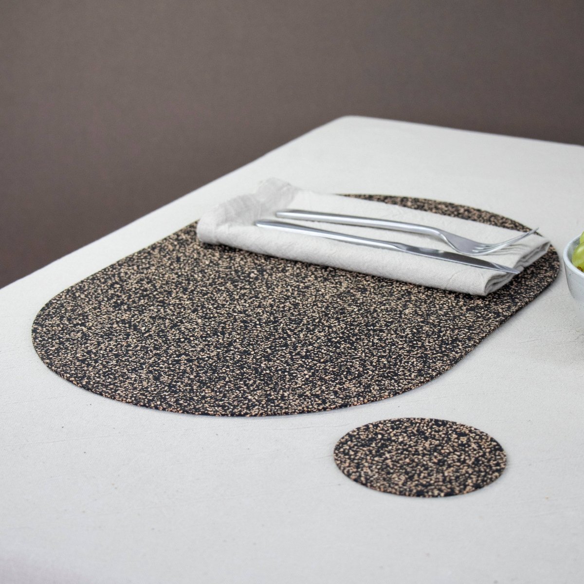 Oval Dash Cork Placemat with flatware setting and matching dash coaster from Texas Cork Company