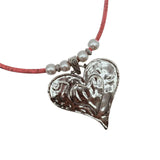 Heart-shaped silver pendant on a pink cord with pearl-like beads