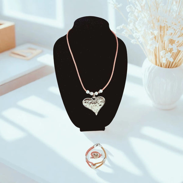 Necklace with a heart pendant on pink cork cord with bracelet and ring with heart charms  on a black stand.