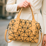 Taos cork handbag with black geometric pattern held by a person wearing a white coat.