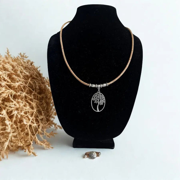 Necklace with a tree of life pendant on a black velvet stand  and a coordinating cork ring with a light background
