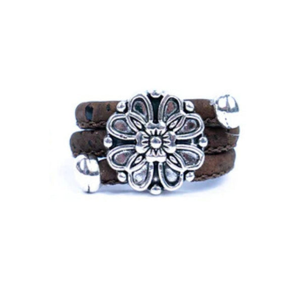Brown cork ring with a silver vintage floral charm on a white background