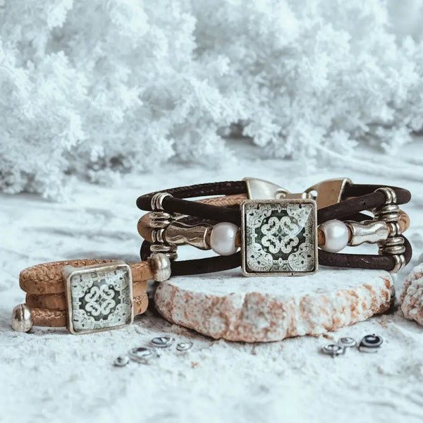 Vintage tile on a cork cord ring and on a bracelet with metal alloy and white beads on a snowy white surface