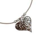 Heart-shaped silver pendant on a white cork cord with pearl-like beads