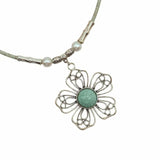 Closeup of front of wire flower pendant with turquoise center on mint colored cork cord