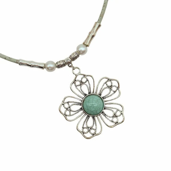 Closeup of front of wire flower pendant with turquoise center on mint colored cork cord